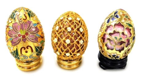 Two Chinese cloisonne enamel eggs on stands, and an egg with gilt metal and floral enamelled overlay. (3)