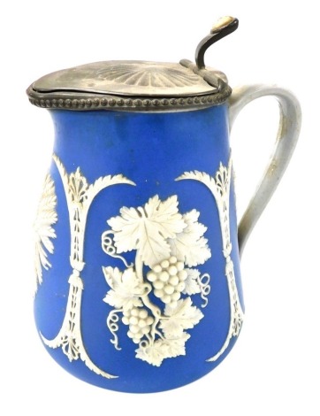 A late 19thC blue stoneware relief moulded jug, with hinged pewter lid and mount, sprig moulded with vines and sheathes of corn, 21.5cm high.