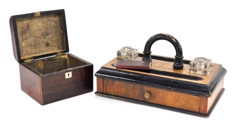 A Victorian walnut and ebonised desk stand, with two glass inkwells, covers lacking, pen recesses, and a frieze drawer, 28cm wide, together with a Victorian rosewood tea caddy, of domed form, 14cm wide. (2)