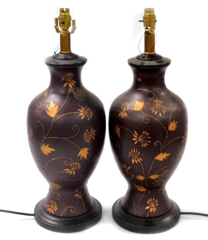 A pair of brown glazed ceramic table lamps, of baluster form, with raised foliate and scrolling leaf decoration, 58.5cm high. Buyer Note: WARNING! This lot contains untested or unsafe electrical items. It is supplied for scrap or reconditioning only. TRAD