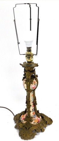 A late 19thC pottery and brass overlaid candlestick, converted to a table lamp, painted with flowers, with floral and foliate scroll cast mounts and base, 66.5cm high.