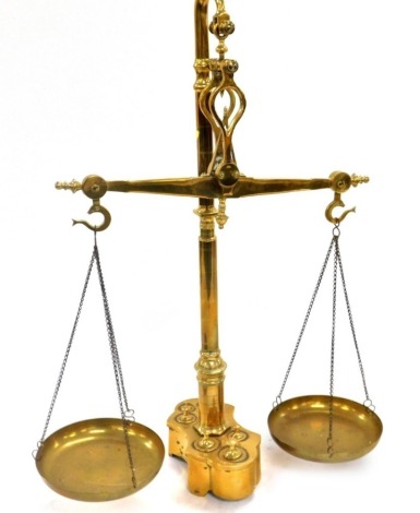 A set of Portuguese brass balance scales, with brass pans, raised on shaped base inset with eight graduated weights, 60cm high.