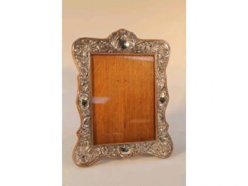 An Edwardian silver repouss? rococo revival picture frame mounted on a wooden frame