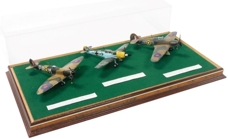 Three World War Two model fighter planes, comprising a Super Marine Spitfire, 609 Squadron Middle Wallop, Hawker Hurricane Mark I, 229 Squadron, Wittering, and a Messerschmitt BF 109E4, France 1940, in a Perspex lidded case, 45.5cm wide.