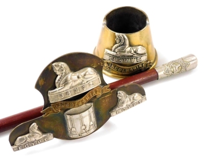 A World War One trench art ashtray, with the badge of Lincolnshire Regiment, brass stand, with badges of the same regiment, and Lincolnshire Regiment swagger stick. (3)