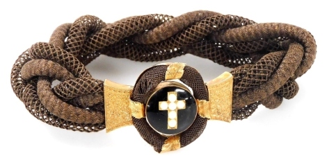 A Victorian mourning bracelet, with a central seed pearl cross on a black enamel ground, with gilt metal mounts, on a woven hair strap.