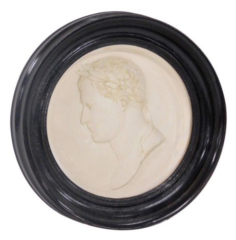 An early 19thC plaster bust of Napoleon Bonaparte, signed Andrieu, bust portrait with a laurel wreath, bears label verso, From One of Andrieu's Collectables 1822, in an ebonised circular frame, 13cm wide.