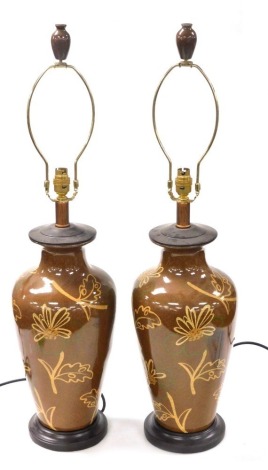 A pair of Chinese brown glazed table lamps, of shouldered tapering form, decorated with flowers and leaves, raised on socle bases, 56cm high. Buyer Note: WARNING! This lot contains untested or unsafe electrical items. It is supplied for scrap or recondit