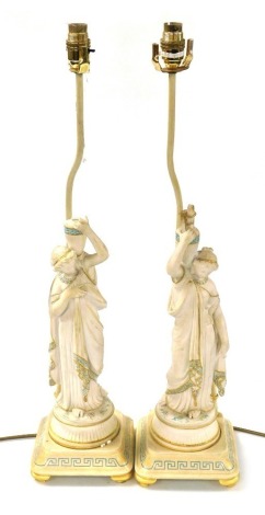 A pair of late 19thC French Parian table lamps, modelled as female water carriers, raised on painted and gilded square wooden bases, with later fittings, 67.5cm high. (AF)