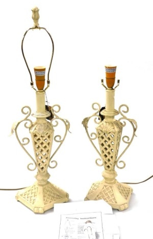 A pair Minister Gift ware cream painted wooden and cast iron table lamps, with leaf scroll handles, and pierced and floral decorated body, 53cm high.