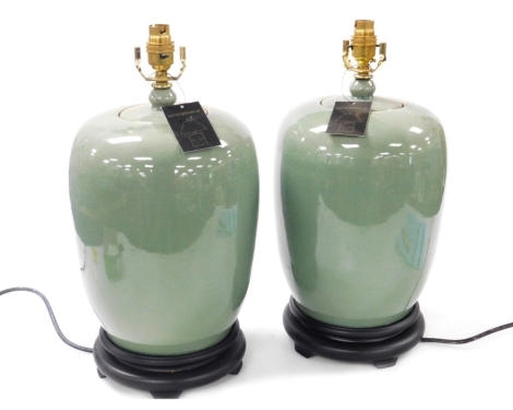 A pair of Chinese celadon vase and cover table lamps, raised on socle bases, 44cm high. Buyer Note: WARNING! This lot contains untested or unsafe electrical items. It is supplied for scrap or reconditioning only. TRADE ONLY