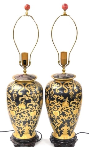 A pair of Chinese ceramic table lamps, of shouldered baluster form, gilt decorated with scrolling leaves and flowers, raised on hardwood bases, 57cm high.