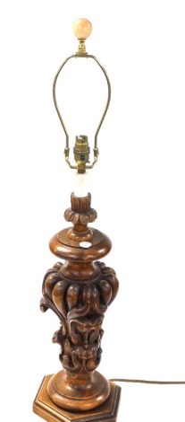 A Spanish carved wooden table lamp, with foliate scroll body, raised on a hexagonal base, 79cm high.