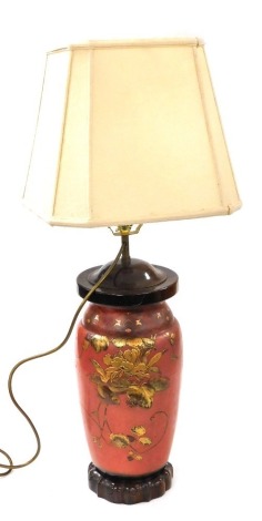 A Japanese red and gilt lacquer table lamp, decorated in bass relief with birds and flowers, raised on a hardwood stand, with shade, 78cm high.