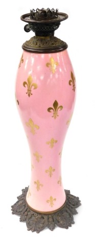 A late 19thC French ceramic and brass table lamp, of baluster form, the body decorated with fleur-de-lis against a pink ground, raised on a floral base, no chimney or shade, 64cm high.