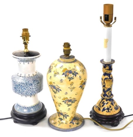 A Chinese porcelain candlestick table lamp, gilt decorated with scrolling flowers against a blue ground, 52cm high, a papier mache table lamp, of baluster form, painted with flowers, 37cm high, and a Chinese blue and white ceramic table lamp, decorated wi