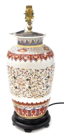 A Chinese ceramic table lamp, of shouldered vase form, decorated with a band of flowers and scrolling leaves against cream ground, raised on a circular wooden socle base, 51cm high. Buyer Note: WARNING! This lot contains untested or unsafe electrical item