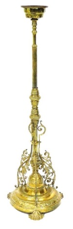 A Victorian brass standard oil lamp base, with a fluted column and scrolling arms, raised on a circular base and three foliate capped feet, 134cm high.