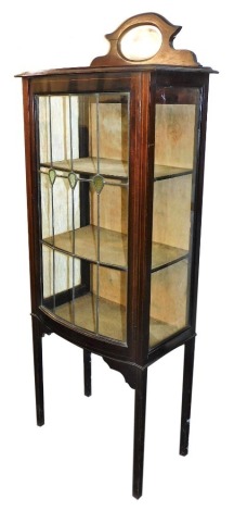 A Victorian mahogany and boxwood line inlay bow fronted display cabinet, with a mirror inset pediment over a pair of glass and partially stained glass doors, enclosing two shelves, raised on tapering square legs, 161cm high, 61cm wide, 38cm deep.