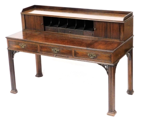 A George III mahogany writing table, the upper superstructure with two sliding tambour fronted doors opening to reveal seven divisions above three drawers, over three frieze drawers, raised on channelled square legs on block feet, 104cm high, 140.5cm wide