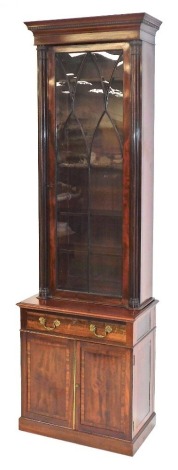 A Victorian mahogany cupboard bookcase, of narrow proportions, the dentil moulded pediment over an astragal glazed door enclosing five shelves, flanked by stylised fluted pilasters, above a base with frieze drawer over a pair of cupboard doors, on a plint