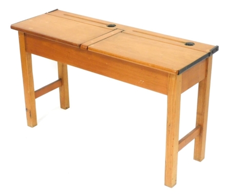 An early 20thC oak and beech twin school desk, with two hinge lids, with pen recesses and inkwell recesses behind, raised on square legs united by stretchers, 54cm high, 103cm wide, 36cm deep.