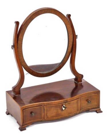 An Edwardian mahogany and boxwood banded serpentine toilet mirror, with an oval swing frame mirror, the base with one long and two short drawers, raised on bracket feet, 49cm high, 39cm wide.