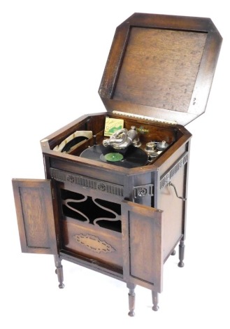 An early 20thC Gilbert oak cased cabinet gramophone, for A Hinkins and Son, Retford, the hinged lid opening to reveal a fitted interior, with 78rpm records, above two doors enclosing a sound box, raised on turned legs, 76cm high, 57cm wide, 54cm deep.