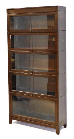 An early 20thC Gunn five sectional bookcase, with up and over doors enclosing graduated interiors, raised on square legs, with an advert for said bookcase, 184.5cm high, 86.5cm wide, 31cm deep.