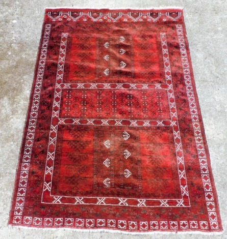 A Turkoman red ground rug, decorated with three central panels of floral and foliate motifs, within repeating floral borders, 266cm x 75cm.