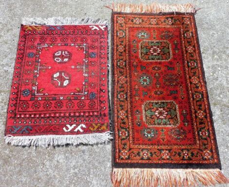 An Afghan red ground prayer rug, decorated with two central medallions within repeating floral borders, 65cm x 49cm, together with an Afghan Turkhoman red ground prayer rug, decorated with two central medallions and flowers within a repeating floral borde