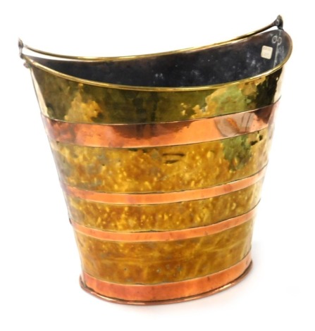 A Victorian brass and copper bound fire bucket, of tapering oval form, with swing handle, 32cm high.