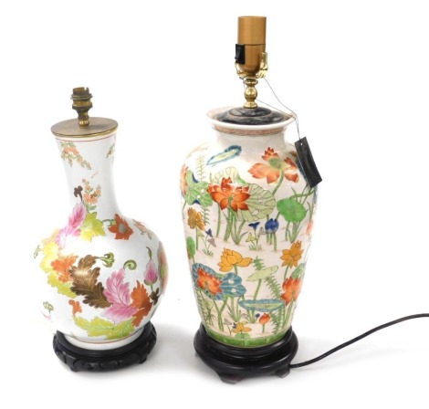 A Chinese pottery table lamp, enamel decorated with water lilies and other flowers, raised on a circular base, 55cm high, together with a porcelain table lamp, decorated with flowers and leaves, on a carved hardwood base, 44cm high. (2) Buyer Note: WARNIN