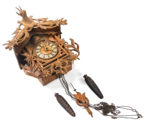 A late 19thC Black Forest cuckoo clock, the circular dial bearing Roman numerals, two train movement, the case of architectural form, with a floral and foliate carved pediment centred by a shield and carved deer's head, the body carved with flowers, with 