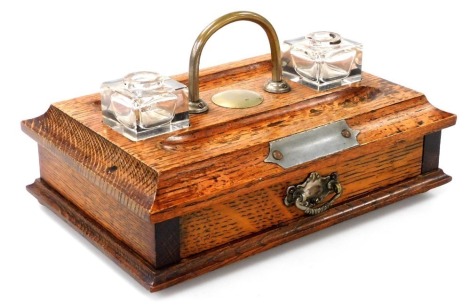 A Victorian oak desk stand, with a brass carrying handle, having two glass inkwells and two pen recesses, over a frieze drawer, raised on a plinth base on bun feet, 28cm wide.