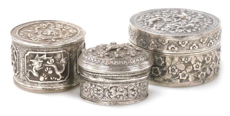 Two Indian white metal trinket boxes, each with embossed decoration, one of cylindrical form, decorated with birds and flowers, 6cm diameter, the other of oval form, decorated with animals, 4.5cm wide, together with a further trinket box, possibly Chinese