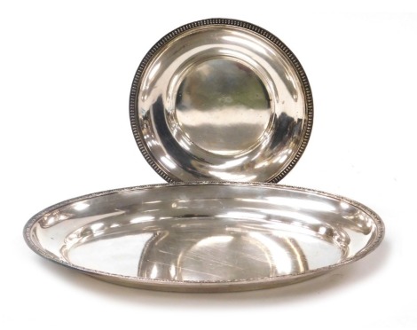 A Continental silver plated oval serving dish, with repeat patterned decorated border, indistinct marks to underside, 40cm wide, together with a further circular serving dish, indistinctly marked, 24cm diameter, each possibly Christofle.