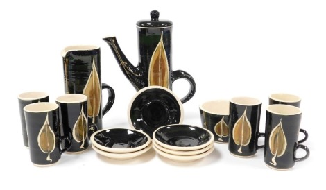 A Stuart Bass Studio pottery part coffee set, decorated with leaves against a green ground, with a cream interior, comprising coffee pot, milk jug, sugar bowl, and six coffee cups and saucers.