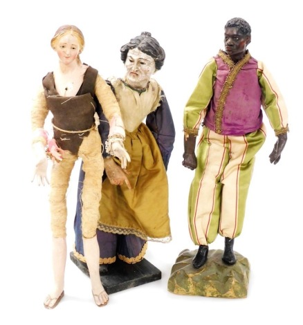 Three late 19thC Continental figures, comprising a carved wooden figure of a lady in a silk dress, raised on a wooden base, 35.5cm high, wooden figure of a black gentleman in pantaloons and matching jacket, raised on a wooden base, 39cm high (AF), and a c