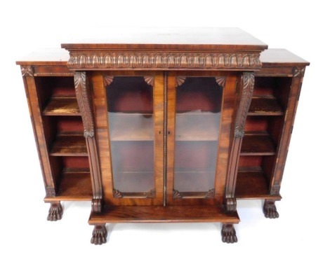 A William IV mahogany breakfront side cabinet, with raised centre top on carved lotus leaves, over two glazed doors, with nulled and fan carved mouldings, enclosed by an acanthus scroll column support flanked by open shelves, raised on carved paw feet wit