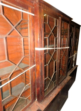 A George III mahogany breakfront library bookcase, with a moulded cornice above three pairs of astragal glazed doors enclosing adjustable shelves, the base with three pairs of panelled doors, on a plinth, 294cm high, 447cm wide, 45cm deep. (AF)