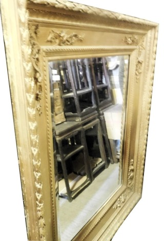 A late 19thC giltwood and gesso wall mirror, the frame decorated with fruit, leaves, flowers, etc., surrounding a bevelled mirror plate, 164cm high, 138cm wide.