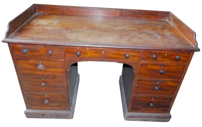 An early Victorian Gillows mahogany kneehole dressing table, with a raised gallery above an arrangement of nine drawers, each with turned wood handles, on a plinth, central drawer stamped Gillow Lancaster, 84cm high, 128cm wide, 63cm deep.