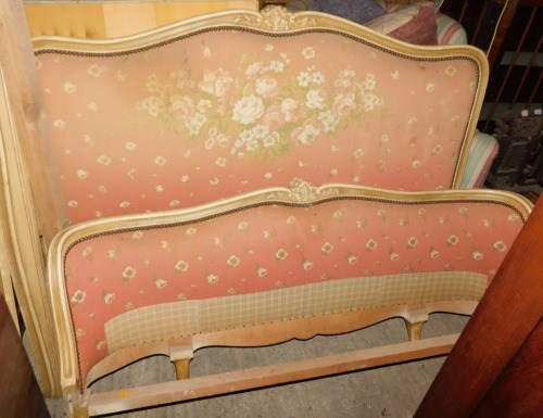 An early to mid 20thC French double bed, with a cream painted show frame, floral upholstered padded back and foot, 150cm wide.