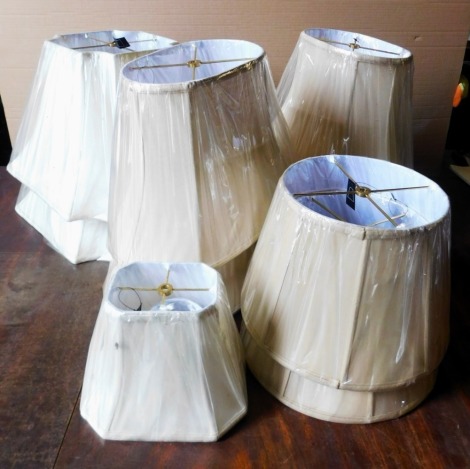 A collection of beige and cream silk lamp shades, various sizes, as new with original shrink wrap.