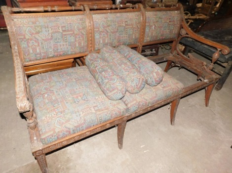 A late 19th/early 20thC mahogany sofa in Egyptian Revival style, elaborately carved with flowers, patera, etc., with triple padded back and seat, winged figure or sphinx arm supports, on sabre legs, 184cm wide. (AF)