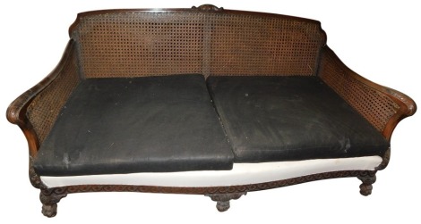 An early 20thC mahogany deep seated bergere sofa, with show frame, caned back and sides, on paw feet.