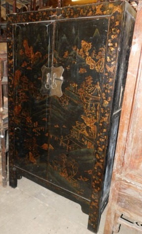 A 19thC Chinese black lacquer cupboard, decorated overall with buildings, trees, rocks, etc., in gilt, with two panelled doors enclosing a single shelf on block feet (AF), 186cm high, 112cm wide.