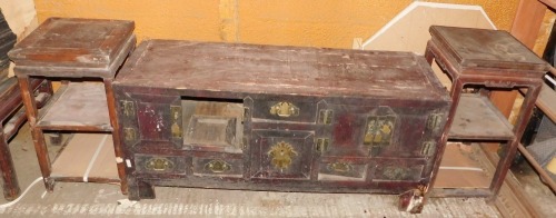 A 19thC Chinese red painted low cabinet, with an arrangement of drawers and doors on block feet, 50cm high, 132cm wide, and two Chinese urn tables, (3).