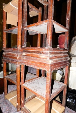 A pair of Chinese elm three tier urn stands or tables, each with a carved frieze on shaped legs, 69cm high, 39cm wide, and two others similar. (4, AF)